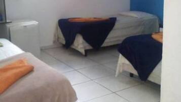 A room with two beds, a window with blinds, a radiator, and a tiled floor.