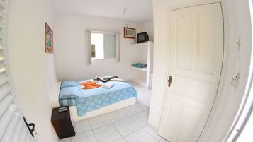 A bedroom with a bed, a television, a window, and a door.