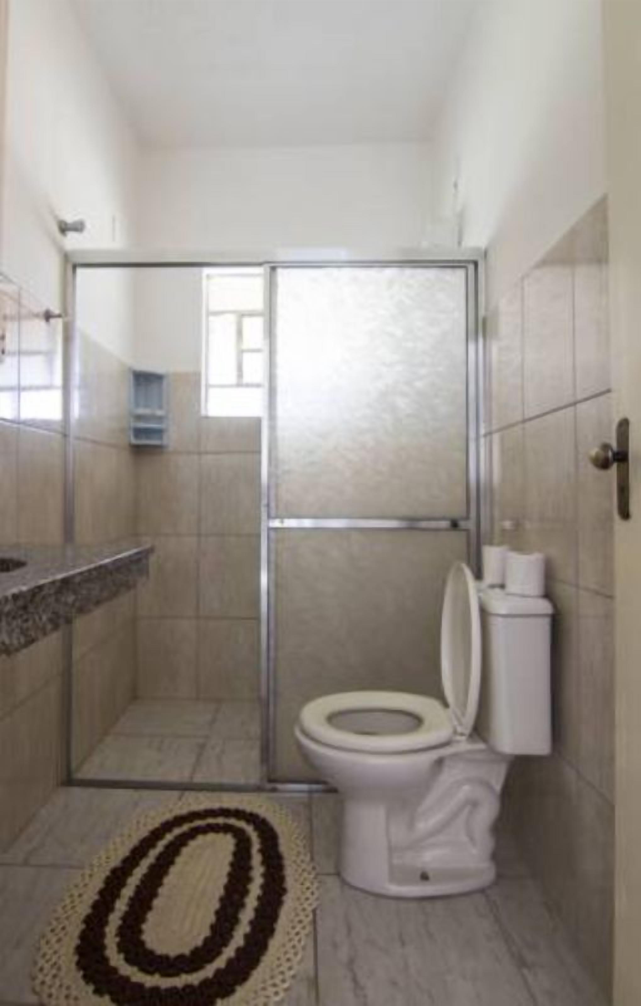 A bathroom with a shower enclosure, a toilet, and a sink.