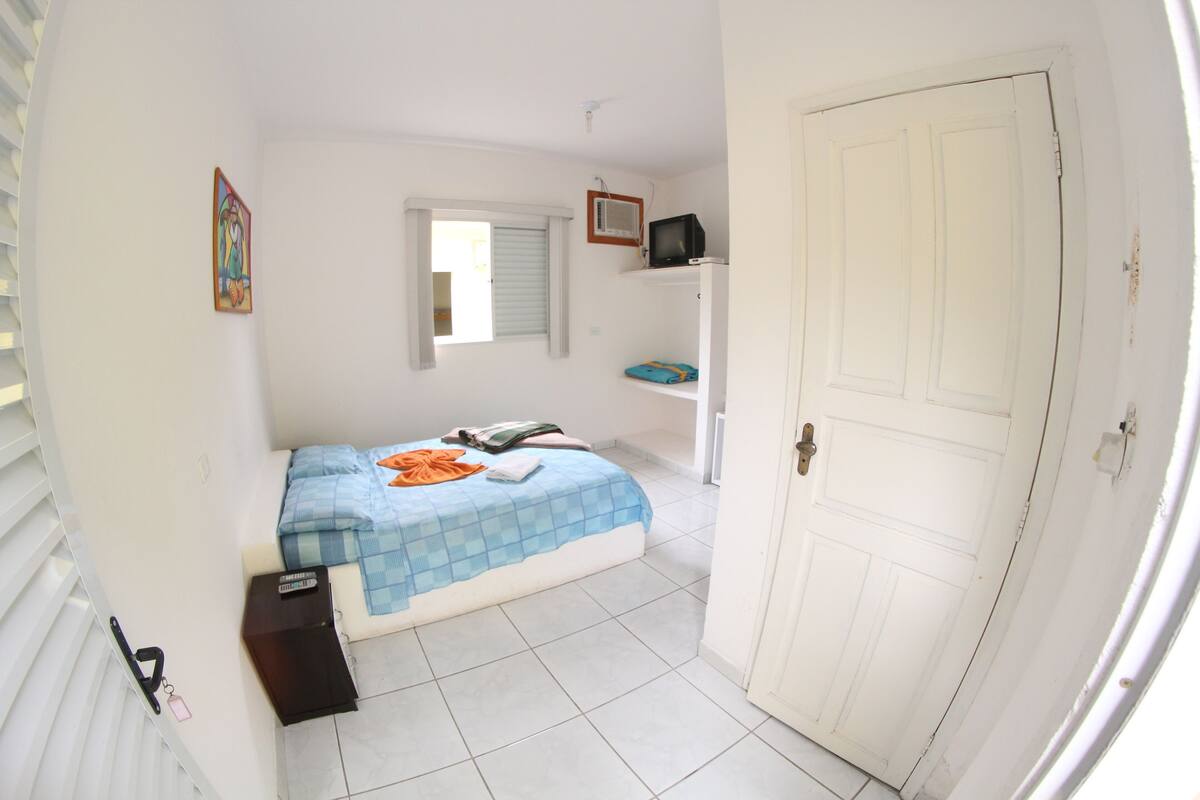 Une chambre à coucher avec un lit, une télévision, une fenêtre et une porte.