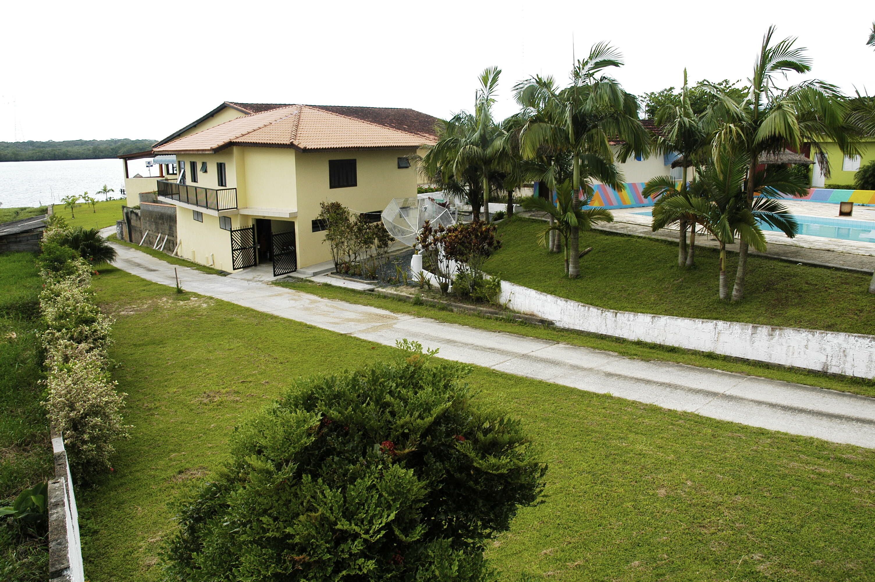 Una casa de dos pisos con balcón, piscina y palmeras.