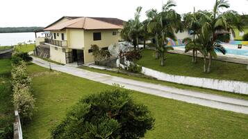 Una casa de dos pisos con balcón, piscina y palmeras.