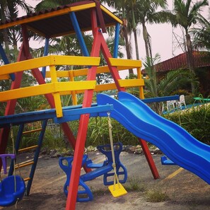 A playground with a blue slide and a climbing structure with yellow and red bars.
