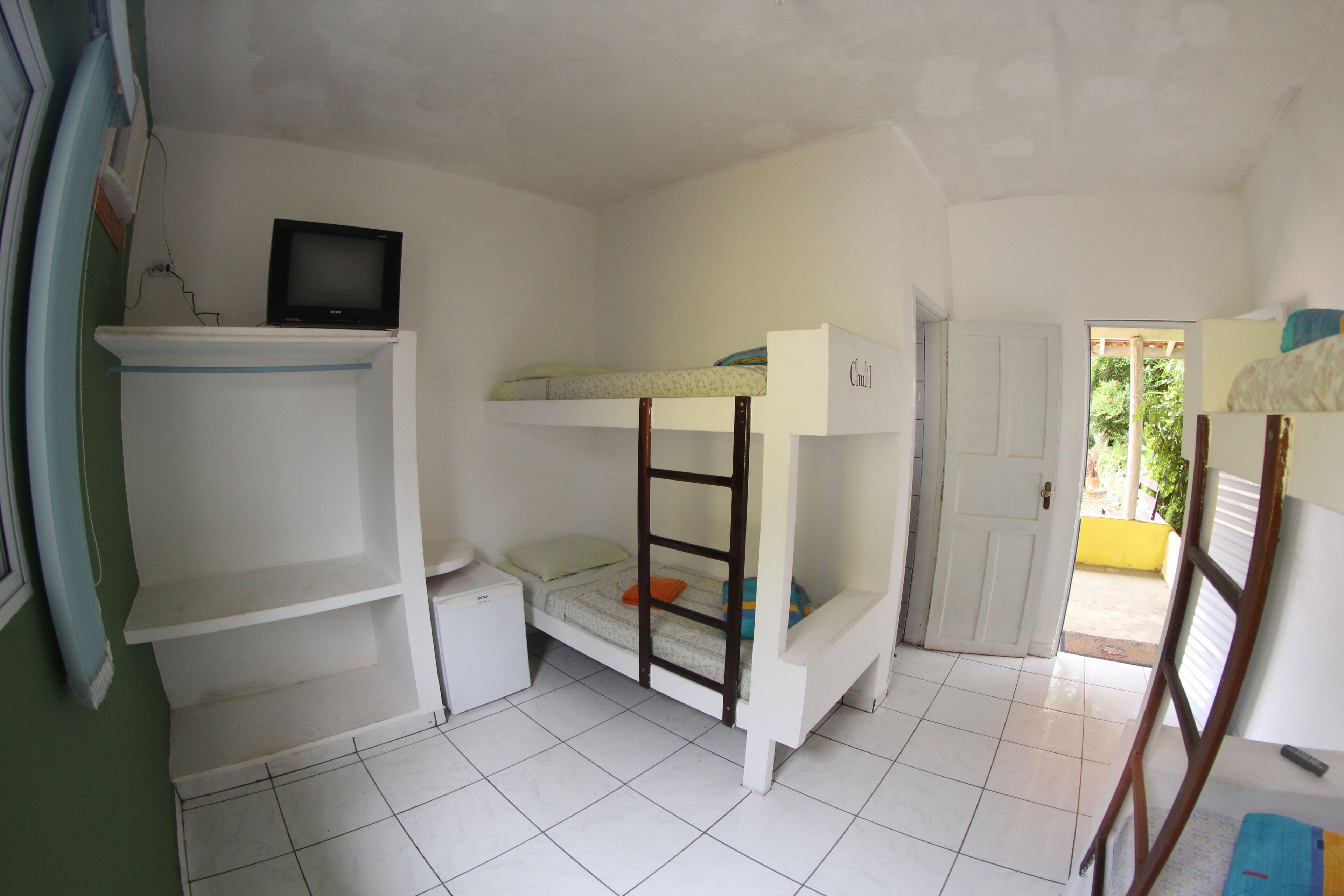 A small, clean room with bunk beds, a television, and a door leading outside.