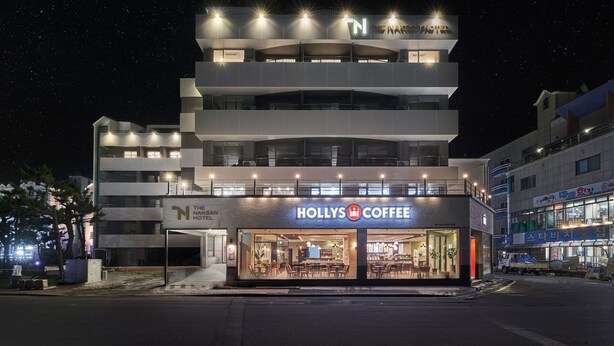 Een meerlaags hotel met een koffiebar op de begane grond, met een modern ontwerp en verlichte borden.