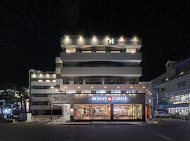 A multi-story hotel with a coffee shop on the ground floor, featuring a modern design and illuminated signage.