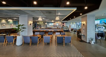 A modern restaurant with a bar area, seating arrangements, and a patterned floor.