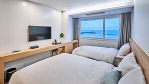 Een hotelkamer met een groot bed, een bureau met een televisie en een raam met uitzicht op zee.