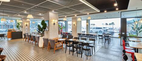 Un café moderno con suelo a cuadros, mesas y sillas de madera.