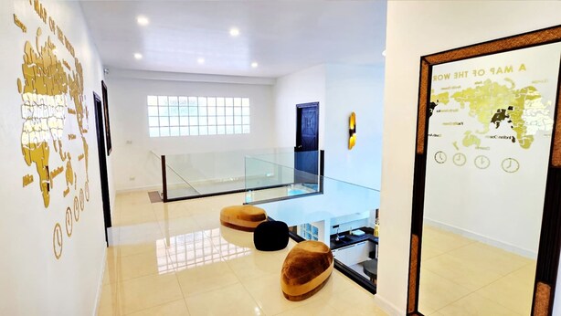 A modern interior with a glass staircase, a map on the wall, and a kitchen area. - GOLDLAND Luxury Pool Villa Pattaya Walking Street 8 Bedrooms (Pattaya)