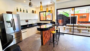 A modern kitchen with a central island, stainless steel appliances, and a view of an outdoor dining area. - GOLDLAND Luxury Pool Villa Pattaya Walking Street 8 Bedrooms (Pattaya)