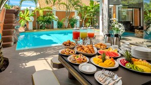 A breakfast buffet with tropical fruit, pastries, and beverages by a poolside. - GOLDLAND Luxury Pool Villa Pattaya Walking Street 8 Bedrooms (Pattaya)