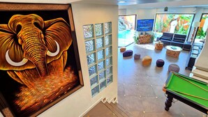 A pool table in a room with a large elephant painting, a TV, and a seating area with ottomans. - GOLDLAND Luxury Pool Villa Pattaya Walking Street 8 Bedrooms (Pattaya)