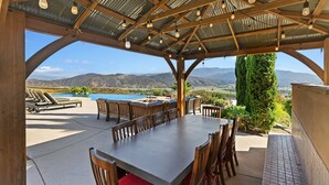 An outdoor dining area with a view of mountains and a pool.