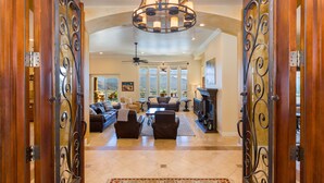 A spacious living room with a fireplace, a large chandelier, and a view of the mountains through the windows.
