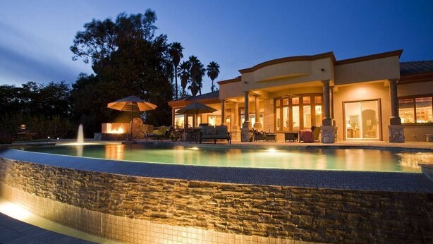 A modern house with a swimming pool, outdoor furniture, and a fire feature.