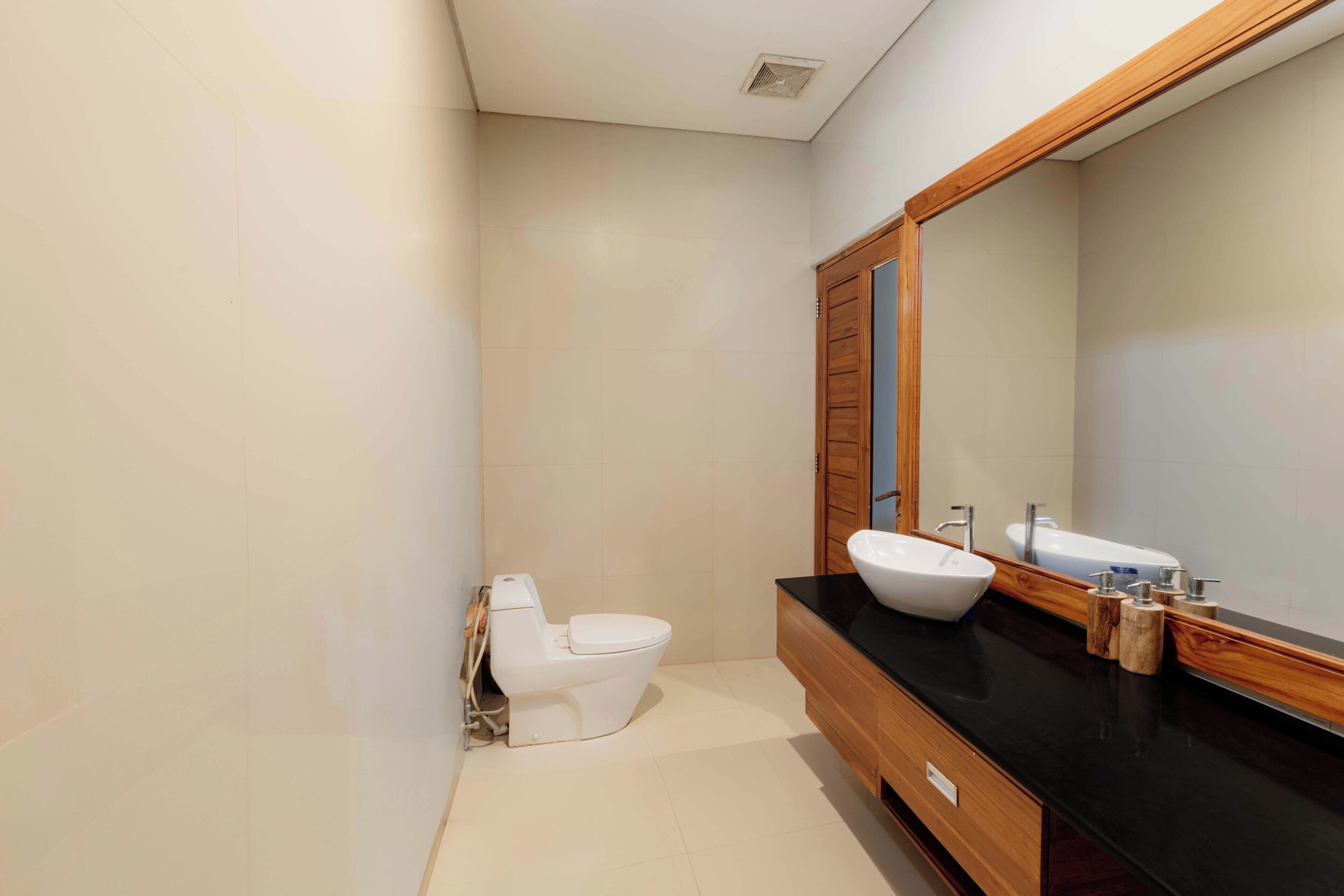 Un baño moderno con inodoro, dos lavamanos y un espejo grande.