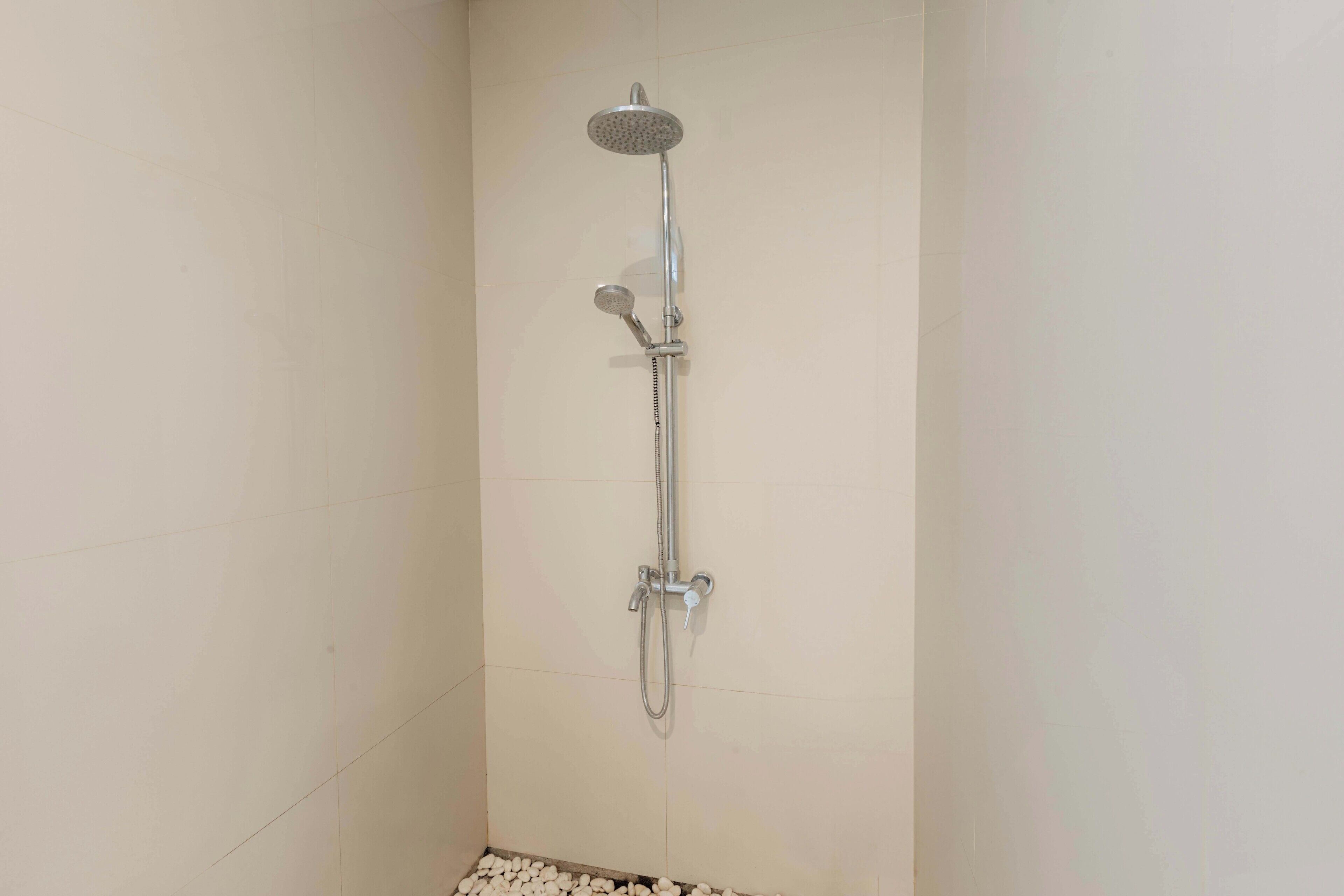 A shower with a handheld showerhead and a fixed showerhead mounted on the wall.