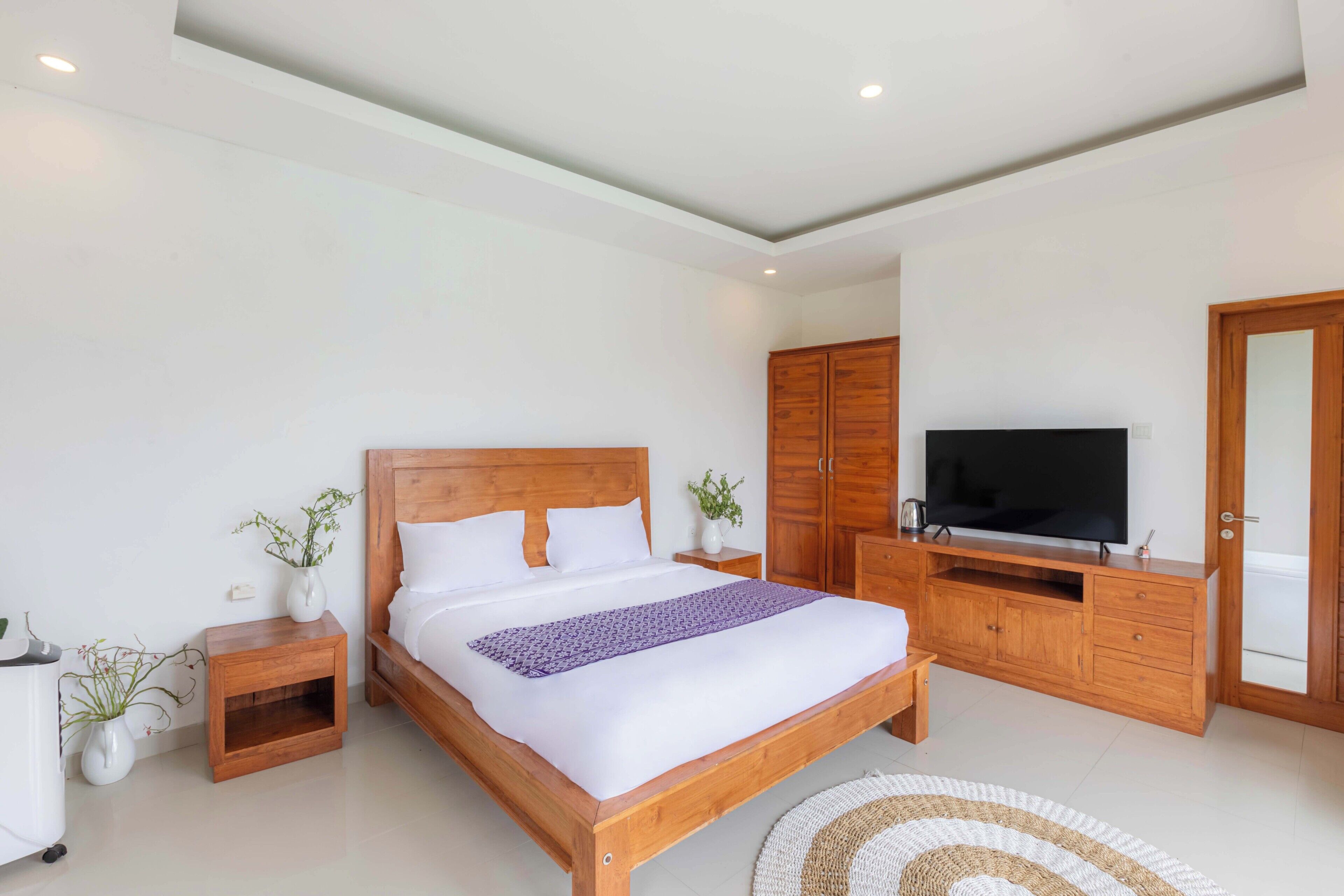 Un dormitorio moderno con una cama de madera, un televisor y un armario.