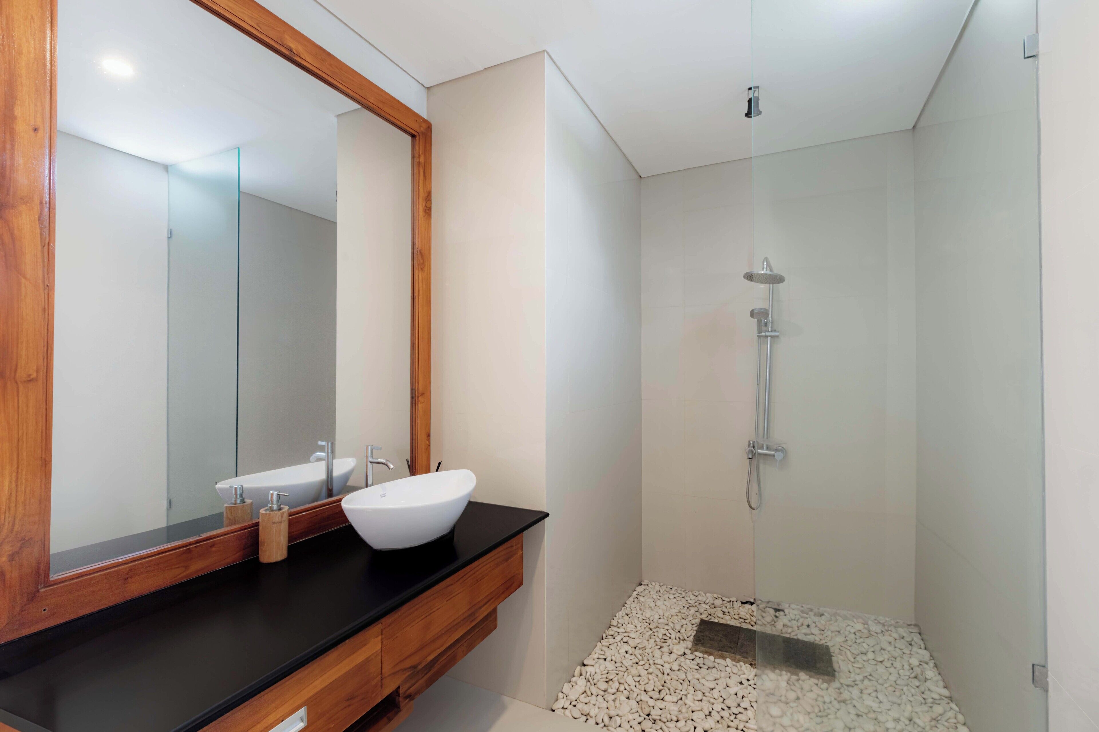 Une salle de bain moderne avec un meuble-lavabo en bois, un lavabo blanc et une cabine de douche en verre.