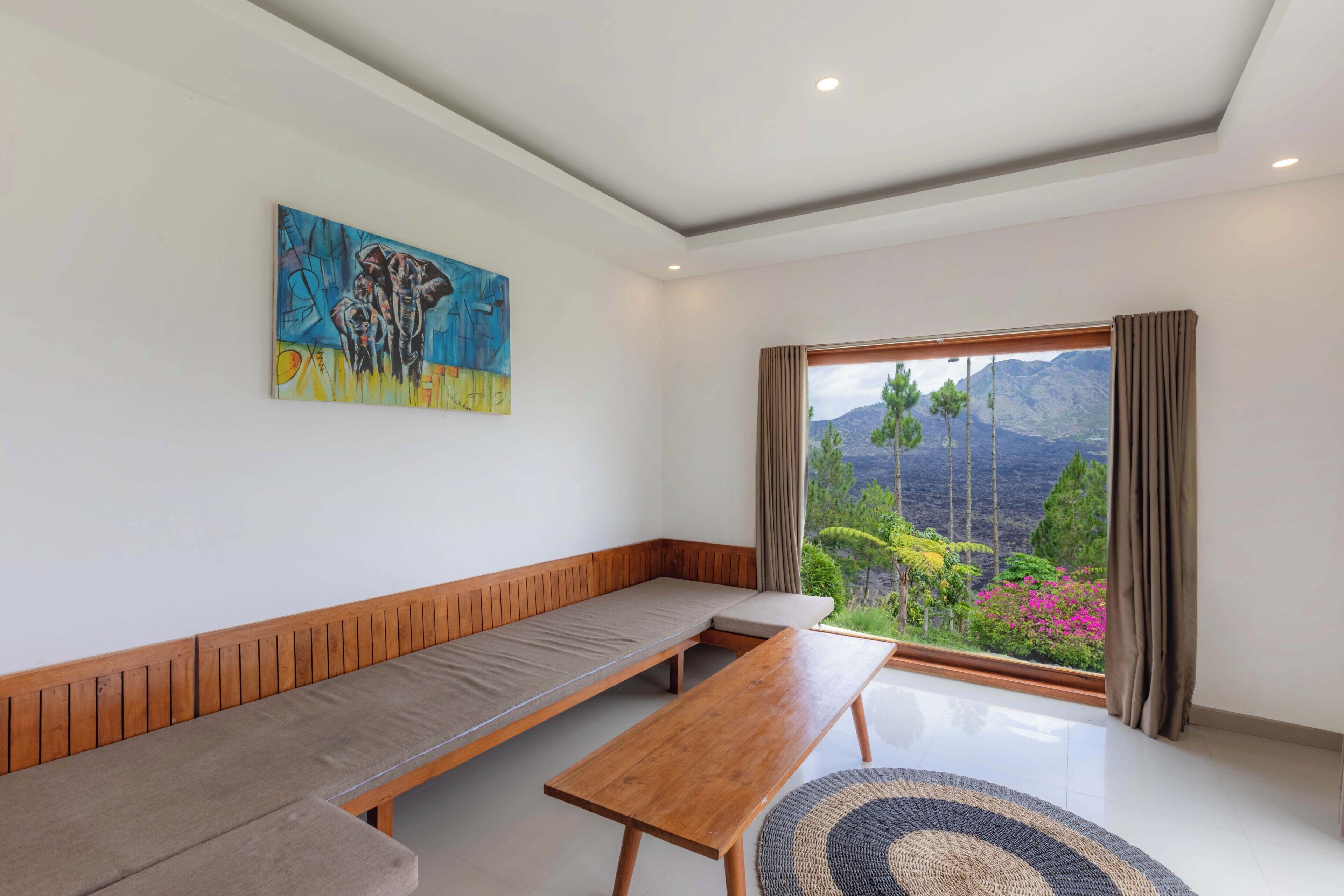A room with a wooden bench, a sofa, and a painting on the wall.