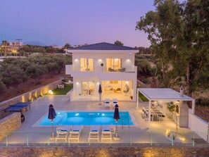 Une maison moderne à deux étages, dotée d’une piscine, d’un espace extérieur aménagé et offrant une vue sur le paysage environnant.