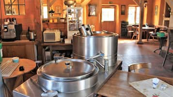 Une cuisine rustique avec des casseroles en acier inoxydable, une machine à café et des meubles en bois.