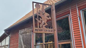 Ein rustikales Gebäude mit einem verwitterten Metallschild mit der Aufschrift "RUMPFSTILZ" und einem traditionellen roten Ziegeldach.