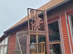 Un bâtiment rustique, orné d’une enseigne en métal patiné sur laquelle on peut lire « RUMPFSTILZ », et coiffé d’un toit traditionnel recouvert de tuiles rouges.