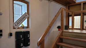 Una escalera de madera que lleva a un rellano con una ventana y una puerta con la leyenda 