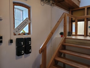 A wooden staircase leading to a landing with a window and a door labeled "GÄSTHAUS". - Holiday room 1 - RUMPELSTILZ baking and shower barn (Steinhagen)