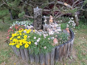 A garden with a wooden fence, various flowers, and decorative statues.