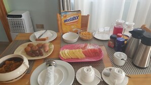 Een ontbijttafel met Weetabix, een kom ontbijtgranen, een bord worstjes, een kom soep en een koffiezetapparaat.