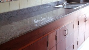 Een keuken met houten kastjes, een granieten aanrechtblad en een betegelde spatwand.