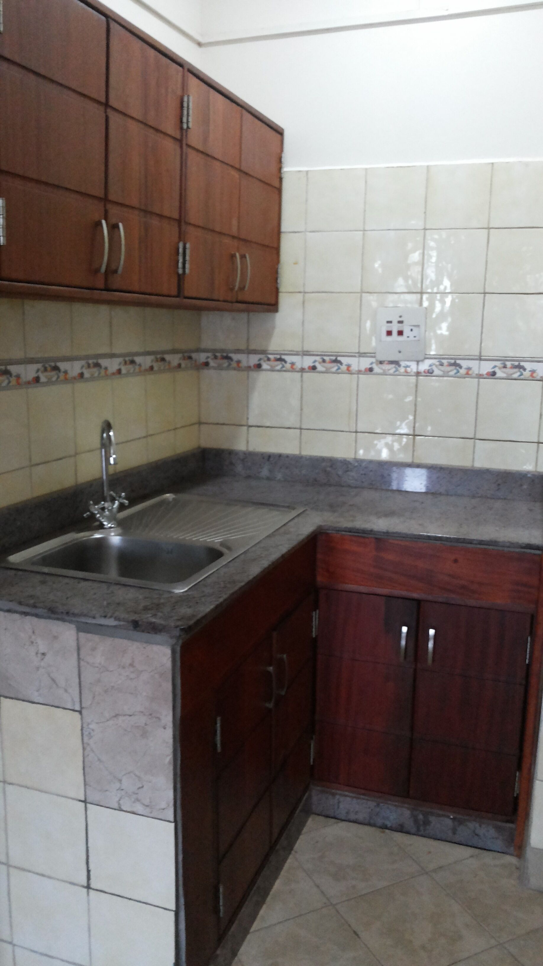 Una cocina con armarios de madera, un lavamanos doble y salpicadero de azulejos.