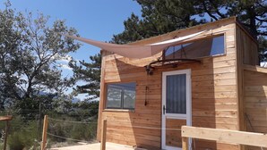 A wooden cabin with a door, windows, and a hanging light fixture. - peggy's tiny (Sisteron)