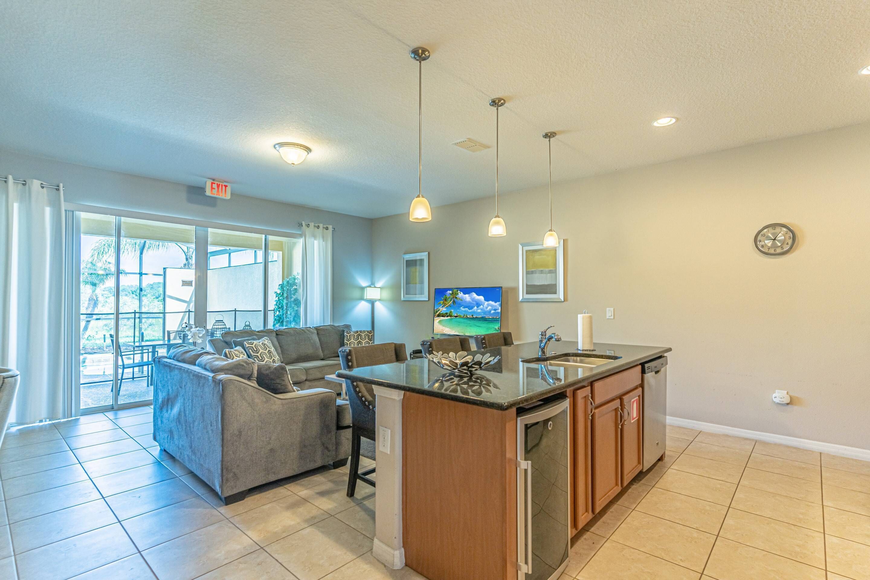 A modern living room with a sofa, a coffee table, and a kitchen area with a sink and cabinets.