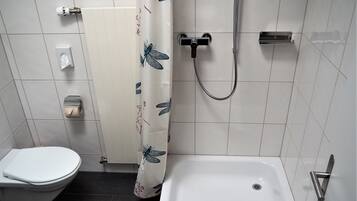 A bathroom with a toilet, a shower, and a bathtub.