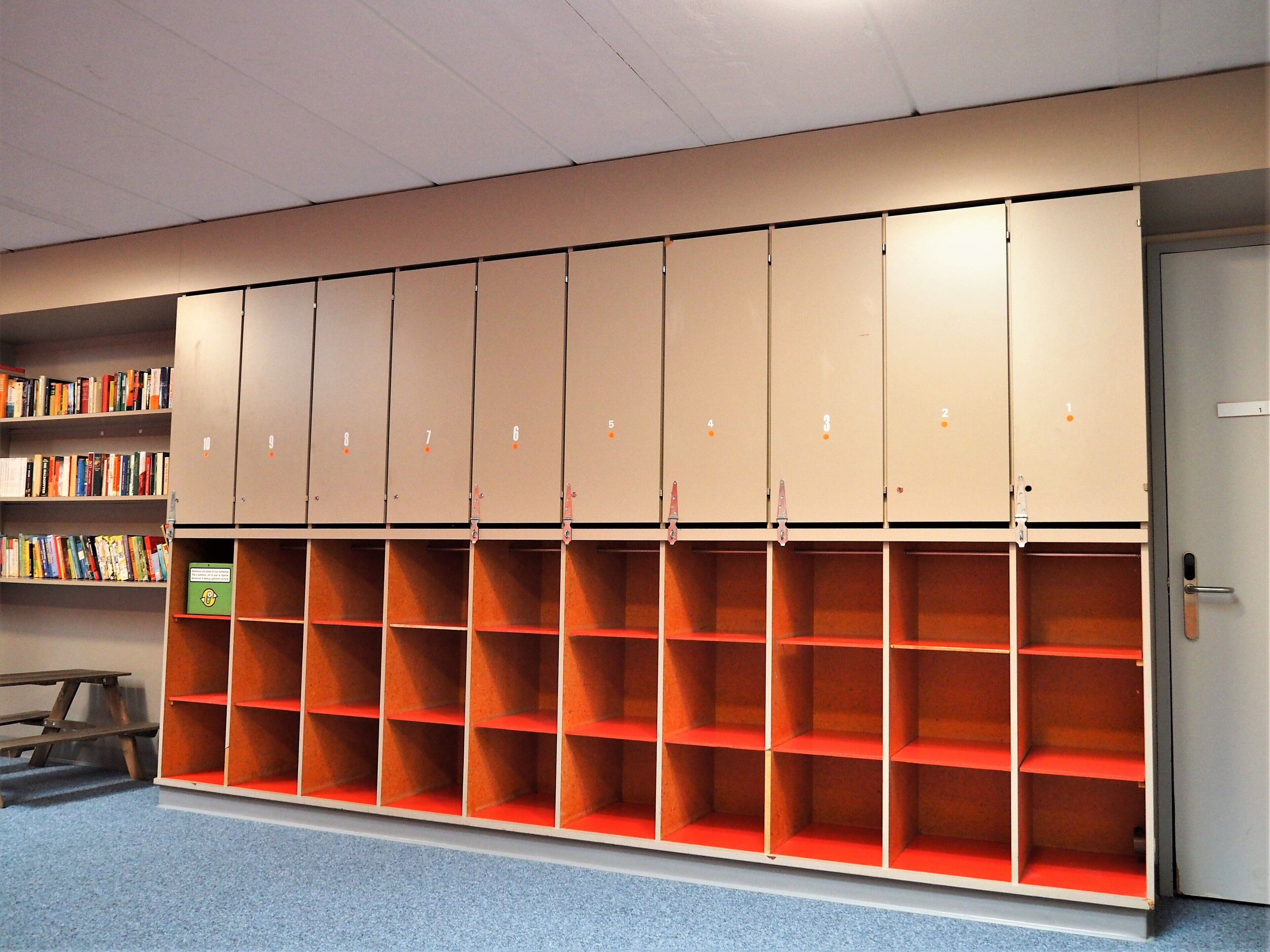 Une bibliothèque avec des étagères et une grande armoire  à casiers numérotés.