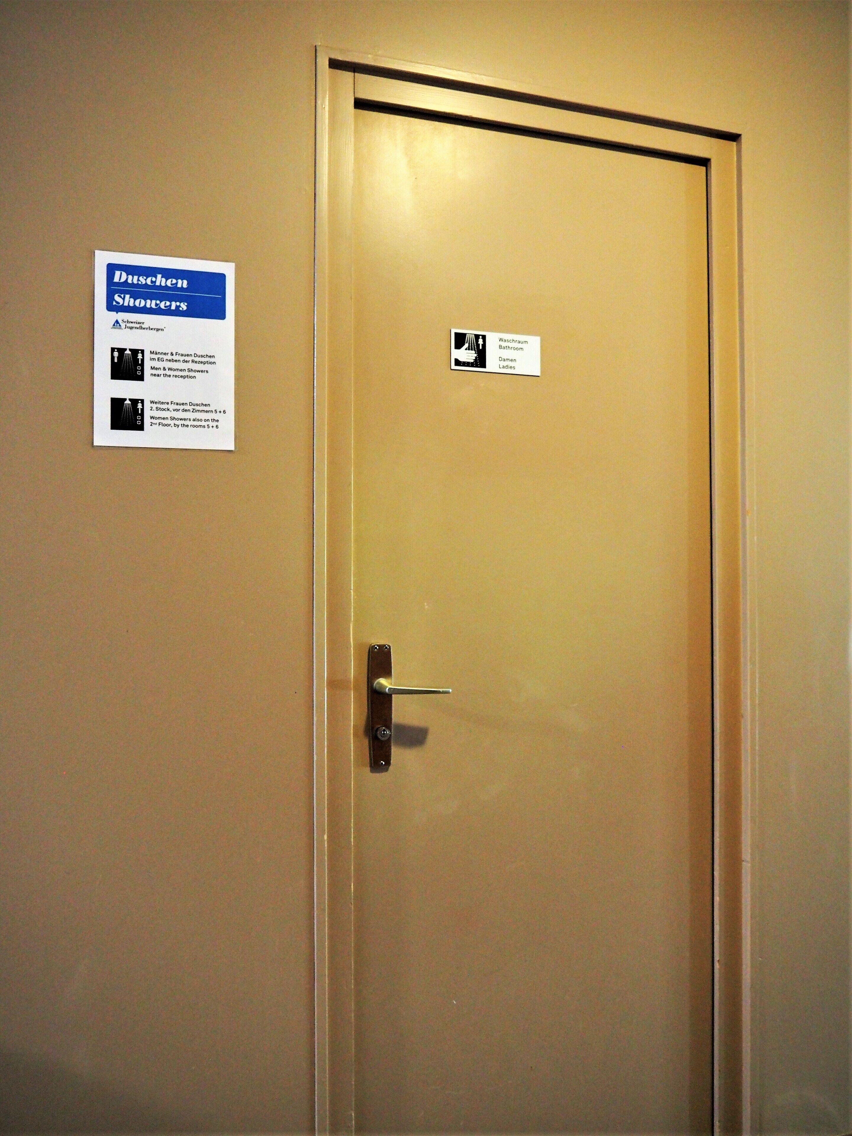 Una puerta con un letrero que indica 'Duschen' (duchas) y 'Waschraum' (baño) para hombres y mujeres.
