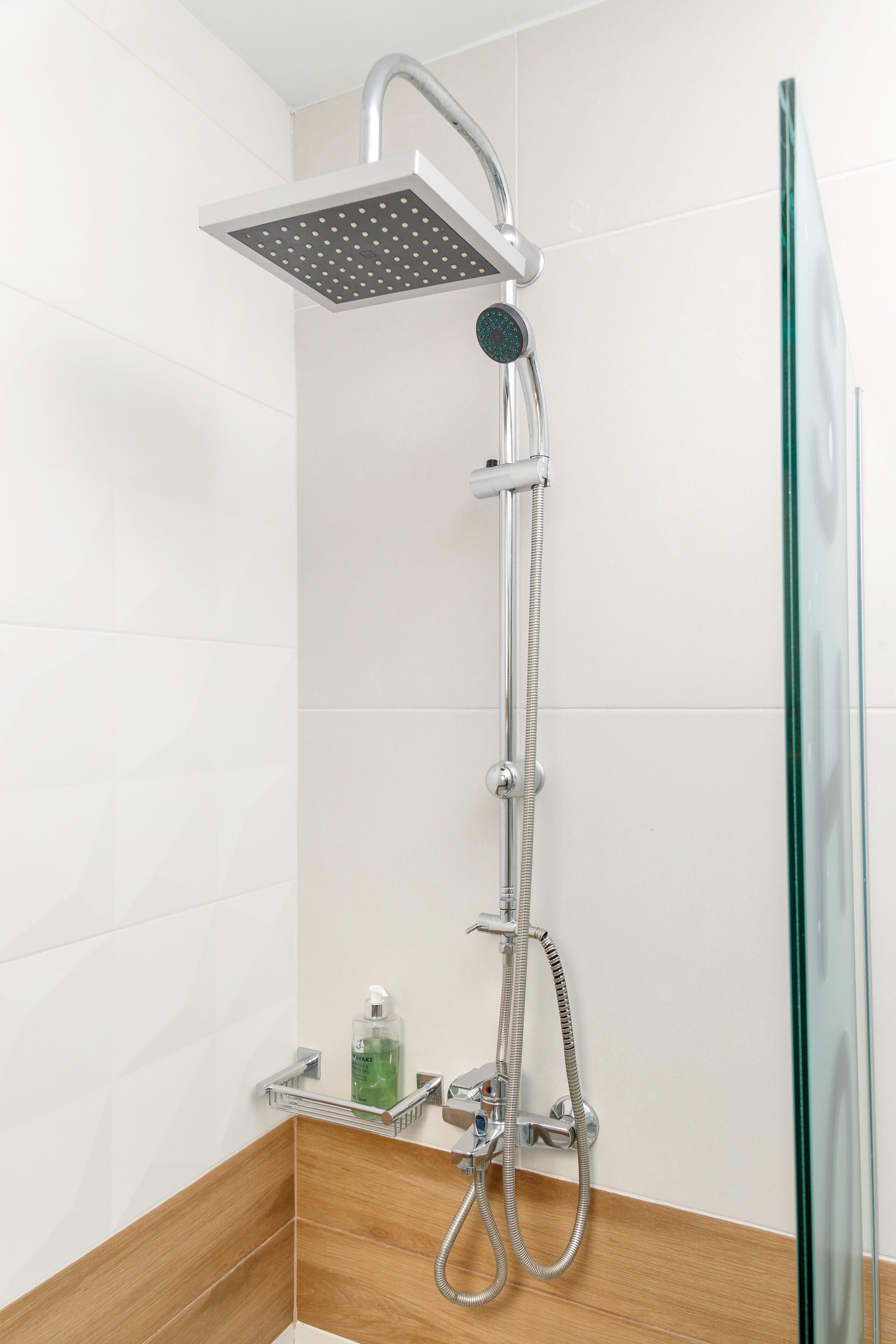 Une douche moderne dotée d’un pommeau de douche carré, d’un pommeau de douche à main et d’un flexible de douche à main.