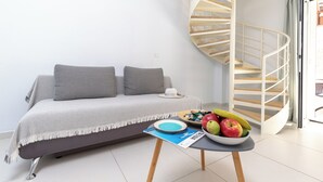 A modern living room with a sofa, a spiral staircase, and a table with a bowl of fruit.