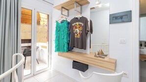 A modern room with a sliding glass door leading to an outdoor area, a wooden shelf with a mirror, and a wall-mounted TV.