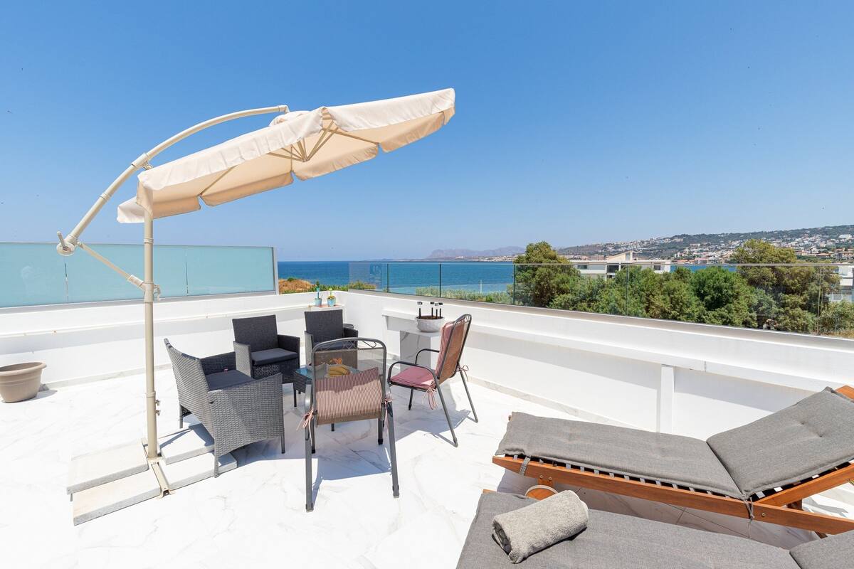 A rooftop terrace with outdoor furniture, a table, and a large umbrella.