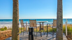 A beachside patio with a table and chairs, overlooking the ocean.