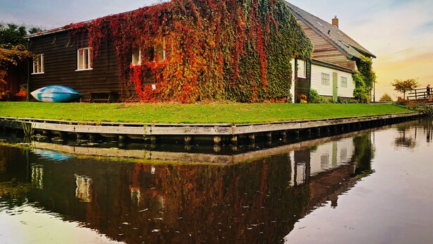 A house with a garden and a body of water in front.