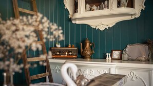 A vintage-style room with a wooden ladder, a white cabinet with decorative items, and a swan-shaped vase.