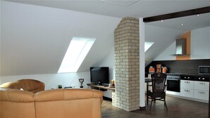 Un loft moderno con techo alto, columna de ladrillo visto y un rincón de estar acogedor.