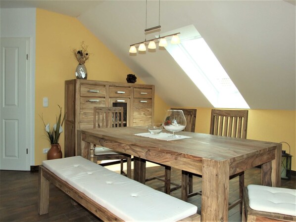 A dining area with a wooden table, benches, and a skylight. - Kranichzug Vacation Apartment - Property ID 120077 (Kargow)