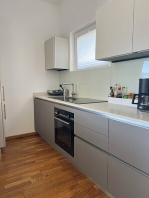 A modern kitchen with a built-in oven, a coffee maker, and a window above the sink.